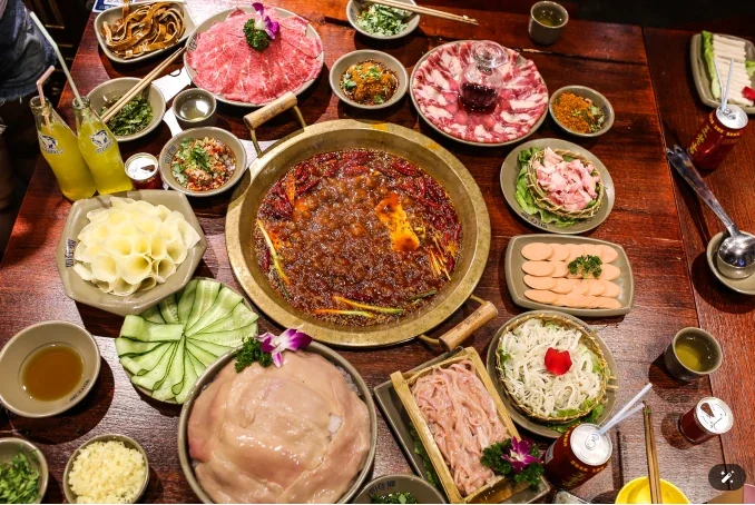 Sichuan hotpot table in Chengdu with divided spicy broth pot and plates of raw ingredients