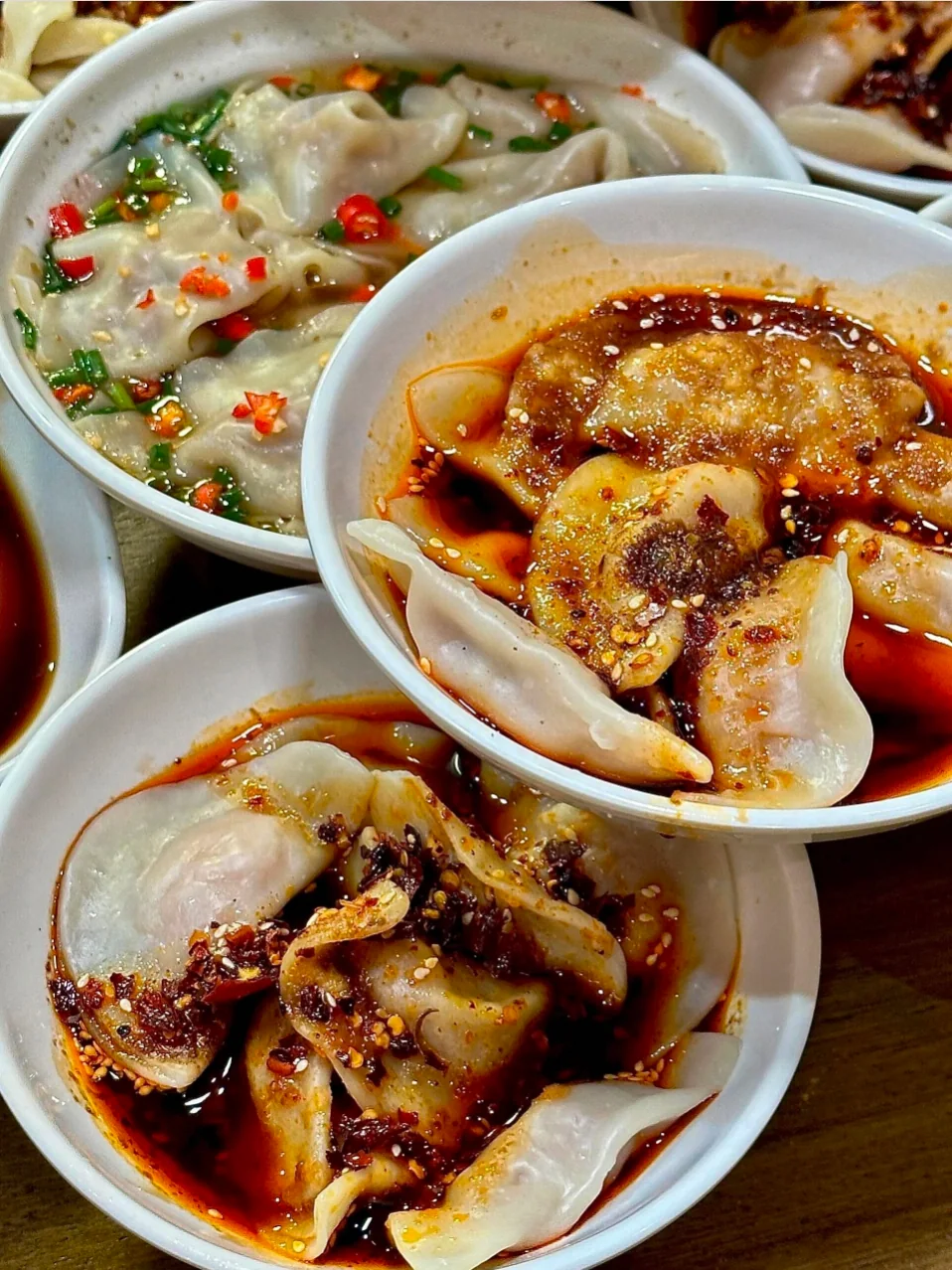 Bowls of Zhong shuijiao dumplings drizzled with sweet chili oil and garlic