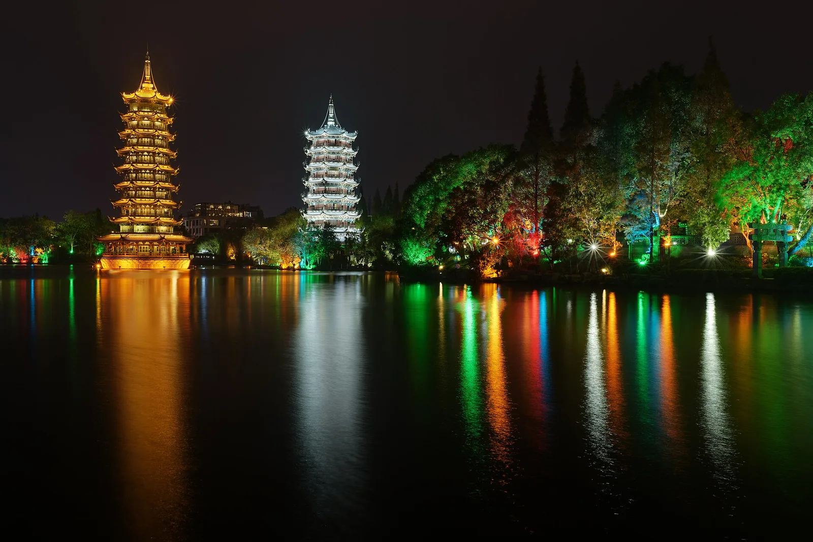 The Sun and Moon Pagodas lit at night and reflected on Shan Lake in Guilin
